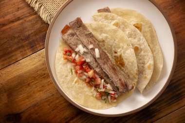 Arrachera Tacos. Meksika kil tabağında buğday tortilla ile marine edilmiş biftek. Meksika 'dan gelen sokak yemekleri, geleneksel olarak kişniş, soğan ve baharatlı sos ya da guacamole ile birlikte..