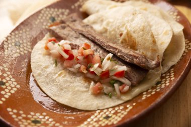 Arrachera Tacos. Meksika kil tabağında buğday tortilla ile marine edilmiş biftek. Meksika 'dan gelen sokak yemekleri, geleneksel olarak kişniş, soğan ve baharatlı sos ya da guacamole ile birlikte..