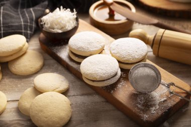 Alfajor. Latin Amerika 'da popüler olan geleneksel bir tatlı, iki kurabiyeyi birleştirip toz şeker, rendelenmiş hindistan cevizi veya çikolatayla kaplı bir sandviç oluşturur..