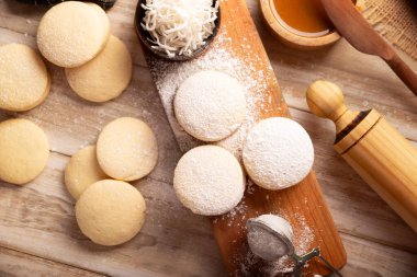 Alfajor. Latin Amerika 'da popüler olan geleneksel bir tatlı, iki kurabiyeyi birleştirip toz şeker, rendelenmiş hindistan cevizi veya çikolatayla kaplı bir sandviç oluşturur..