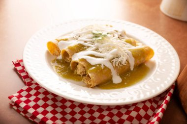 Yeşil enchilada. Tipik Meksika yemeği, doğranmış tavukla doldurulmuş ve baharatlı yeşil sos, krem, rendelenmiş peynir ve soğanla kaplı katlanmış veya sarılmış mısır tortillasıyla yapılır..