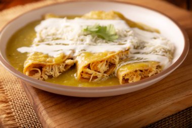 Yeşil enchilada. Tipik Meksika yemeği, doğranmış tavukla doldurulmuş ve baharatlı yeşil sos, krem, rendelenmiş peynir ve soğanla kaplı katlanmış veya sarılmış mısır tortillasıyla yapılır..