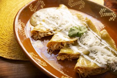 Yeşil enchilada. Tipik Meksika yemeği, doğranmış tavukla doldurulmuş ve baharatlı yeşil sos, krem, rendelenmiş peynir ve soğanla kaplı katlanmış veya sarılmış mısır tortillasıyla yapılır..