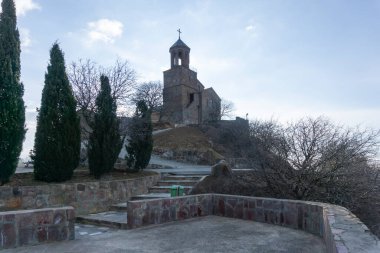 Shavnabada Manastırı 'nın çan kulesi. Taş deposu. Tuğla duvarlar Yapraksız ağaç. Güzel selvi ağaçları. Bulutlu parlak mavi gökyüzü. Georgia.