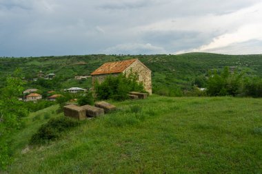 Gürcistan, Saskhori Köyü Kilisesi. Turuncu kiremit çatı, taş duvarlar. Avluda mezar taşları.