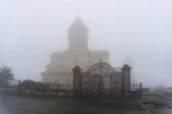 stock image Church in the fog. Beautiful forged gate made of iron rods in the foreground