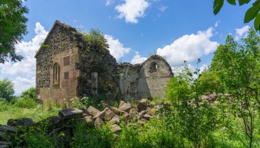 Yeşil çimlerin arasındaki yıkılmış bir kilisenin yan görüntüsü. Ön planda büyük kayalar var. Georgia