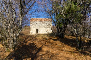 Ormandaki küçük kilise. Döşemeli çatı, taş duvar ve giriş. Sonbahar görünümü ve renkleri.