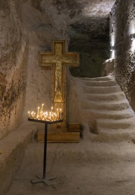 Kilisenin yanındaki mağarada bir haç ve yanan mumlar var. Vardzia bir mağara manastırı, eski bir kaya oyması.