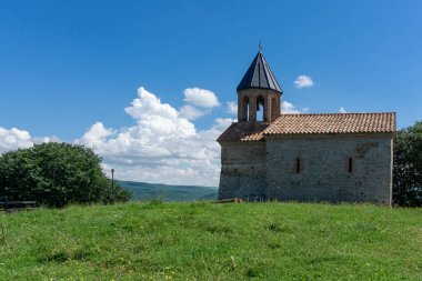 Ortaçağ kilisesi taş ve çan kulesinden yapılmıştır. Gün ışığı, parlak gökyüzü, bulutlar ve yeşil çimenler. Mirzaani.,