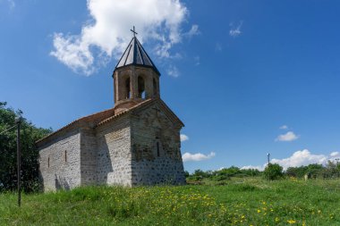 Ortaçağ kilisesi taş ve çan kulesinden yapılmıştır. Gün ışığı, parlak gökyüzü, bulutlar ve yeşil çimenler. Mirzaani.,
