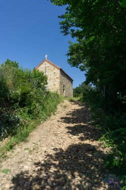 Ağaçların ve çalıların arasından küçük bir kiliseye giden toprak bir yol. Martkopi manastırı, Georgi.