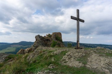 Kojori kalesinin tepesinde. Duvarın yıkıntıları ve taş ve tuğladan yapılmış kule. Uzun tahta haç. Yakınlardaki dağ ve köylerin manzarası. Açık mavi gökyüzü ve bulutlar. Georgia