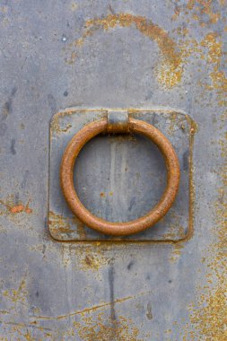 Paslı metal kapıdaki paslı tokmağı yakından izle. Metal ve pas dokusu görülebilir. Georgi.