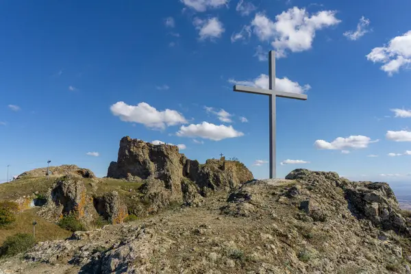 stock image Iron cross on the hill and ruins of the Kojori fortress. Bright blue sky and clouds. Mountains, villages and valley are visible