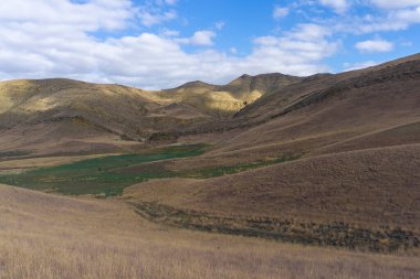 Savannah manzarası. Kurutulmuş portakal otu. Yeşil alan. Dağlar ve bulutlu parlak mavi gökyüzü. Gürcistan 'ın çöl bölgesi.