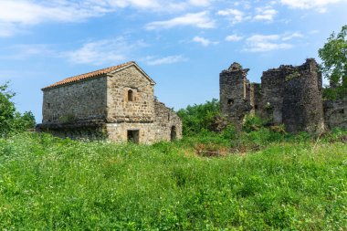 Çimlerle, çalılarla ve ağaçlarla çevrili yeşil bir çayırdaki eski bir kalenin kalıntıları..