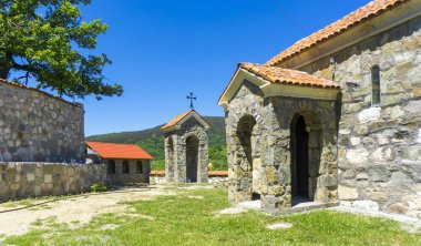 Ortubani manastırının avlusundaki kilise ve çan kulesi. Taş duvarlar ve fayanslı çatı