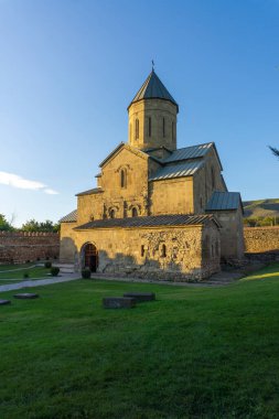 Kale duvarının etrafındaki Tsilkani Katedrali. Yeşil çimenli bahçe. Mezar taşları görünür. Georgia