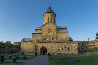 Kale duvarının etrafındaki Tsilkani Katedrali. Yeşil çimenli bahçe. Mezar taşları görünür. Georgia