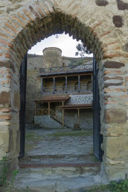 Manastırın bir kısmını kapı aralığından görmek. Taş ve tuğla kemerli giriş, demir kapılar. Tırabzanlar, merdivenler, avlu ve kule görünür durumda. David Gareja manastır kompleksi. Georgia