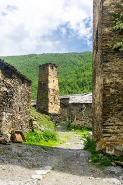 Kuleyle duvarlar arasında dik bir toprak yol var. Ushguli köyünün kale kuleleri ve caddeleri.