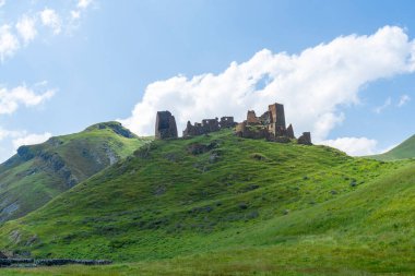 Zakagori fortress on the hill covered with grass. Mountains around clipart