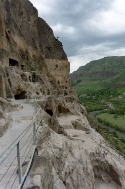 Mağaraların, merdivenlerin ve dağların gündüz manzarası. Vardzia bir mağara manastırı, eski bir kaya oyması.