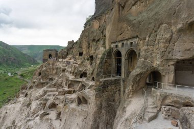 Mağaraların, merdivenlerin ve dağların gündüz manzarası. Vardzia bir mağara manastırı, eski bir kaya oyması.