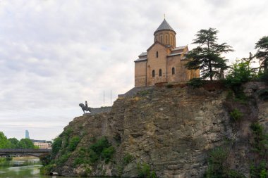 Metekhi Virgin Mary Assumption church and Vakhtang Gorgasali statue on the rock. Mtkvari (Kura) river and bridge clipart