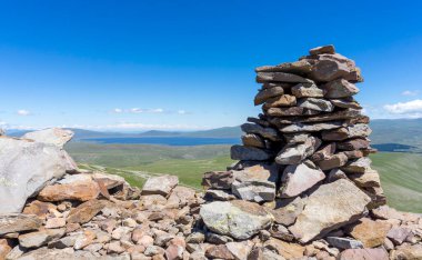 Abuli 'nin tarih öncesi kalesinin duvarındaki tarihi taşların yakın görüntüsü. Paravani gölü, dağlar, bulutlu gökyüzü.