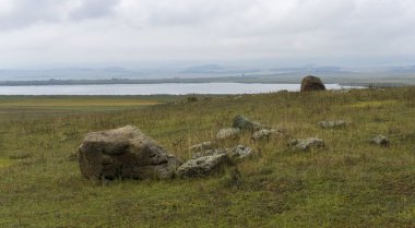 Bareti gölü ve dağları manzarası. Sonbahar otları var. Ön planda liken olan büyük taşlar.