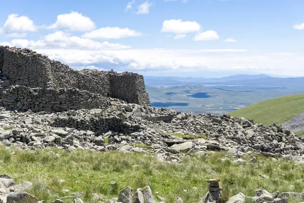 stock image Stone wall and towers of Abuli prehistoric fortress, paravani lake, mountains and clouds. Huge rocks around