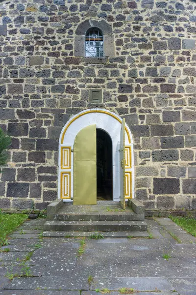 stock image Arched entrance with beautiful ornaments to the Holly Trinity church of Santa village. The walls are made of dark brown stone