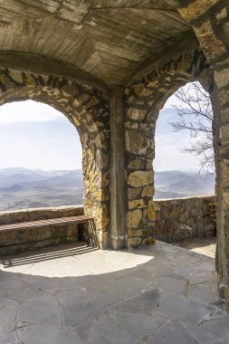 Aziz Peter ve Paul Manastırı 'nın çan kulesinin altındaki bankta. Kayaları ve dağları gören kemerli duvarlar.