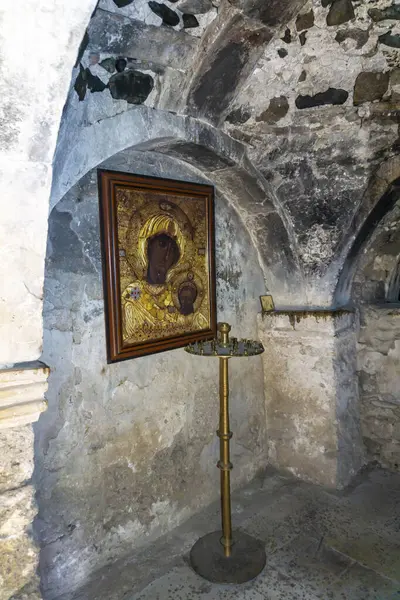 Kilisenin kemerli duvarında Madonna ve Çocuk ikonu var. Mumlar için bakır şamdan.