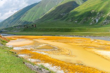 Nehir yatağındaki mineral pınarının akışı. Turuncu, kırmızı, sarı, beyaz tuz renkleri