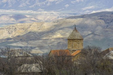 Ertatsminda St. Estate kilisesi kubbesi ve çatıları. Arka planda güneşli tepeler, tarlalar ve dağlar