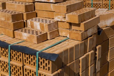 Yeni turuncu tuğlaların bir küpün içine istiflenmiş yan görüntüsü. Alt kısmı yeşil bir kurdeleyle bağlanmış. Kaburgalı, dikdörtgen delikler