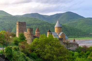 Ananuri Kalesi 'nin genel manzarası. Taş duvar, kuleler, fayanslı çatılar ve kilise kubbeleri. Sıcak akşam ışığı, yağmurlu hava