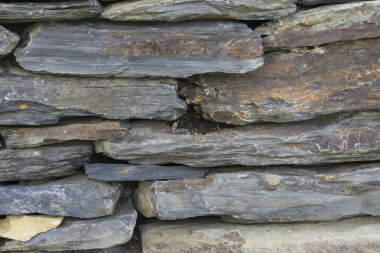 Farklı boylarda ve renklerde taşlarla kaplı taş duvar.