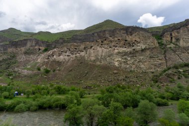 Dağdaki mağaraların ve mavi gökyüzünün genel manzarası. Vardzia, Erusheti Dağı 'nda kazı yapılan bir mağara manastırı. Kafkas, Gürcistan