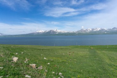 Paravani gölü ve dağları. Doğal göl, mavi su, bulutlar, karlı