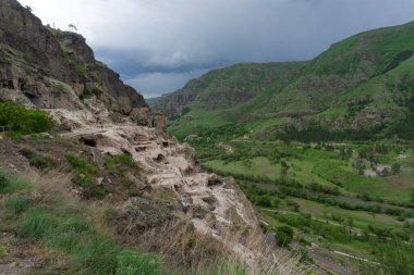 Dağdaki mağaraların, nehir vadisinin ve mavi gökyüzünün gündüz manzarası. Vardzia, Erusheti Dağı 'nda kazı yapılan bir mağara manastırı. Kafkaslar, Georgi.