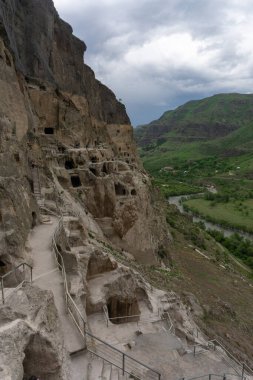 Mağaraların, merdivenlerin ve dağların gündüz manzarası. Vardzia bir mağara manastırı, eski bir kaya oyması.