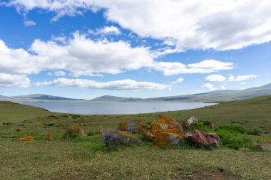 Paravani Gölü 'nün batı kıyısında turuncu yosunlarla kaplı dev taşlar.