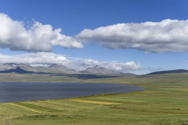 Cultivated agricultural fields, eastern part of Lake Paravani, mountain range covered with clouds clipart