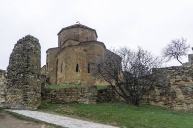 Sabahın erken saatlerinde bulutlu bir havada taştan bir patika Jvari Manastırı 'na çıkıyor. Renksiz gökyüzü, yeşil çimen. Yapraksız ağaçlar