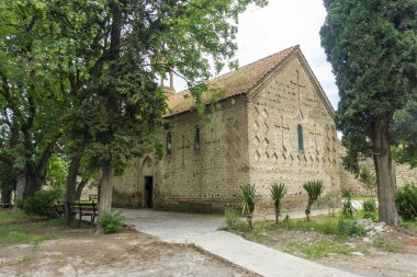Ortaçağ kalesinin bölgesindeki bir kilise. Taş duvarlar, fayanslı çatı. Güzel uzun selvi ağaçları.