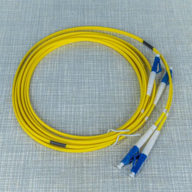 Sarı renkli optik kablo mavi konnektörlü bir halka içine sarılmış.